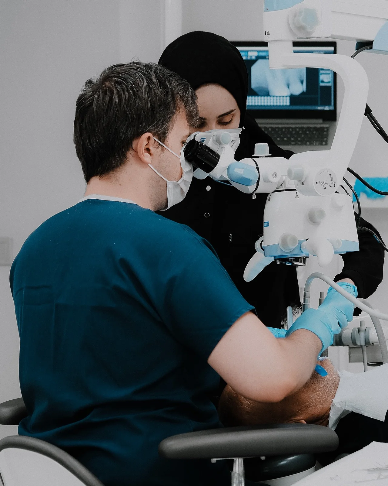 Dental mikroskopla kanal tedavisi: hekim mikroskop başında, ekranda periapikal görüntü