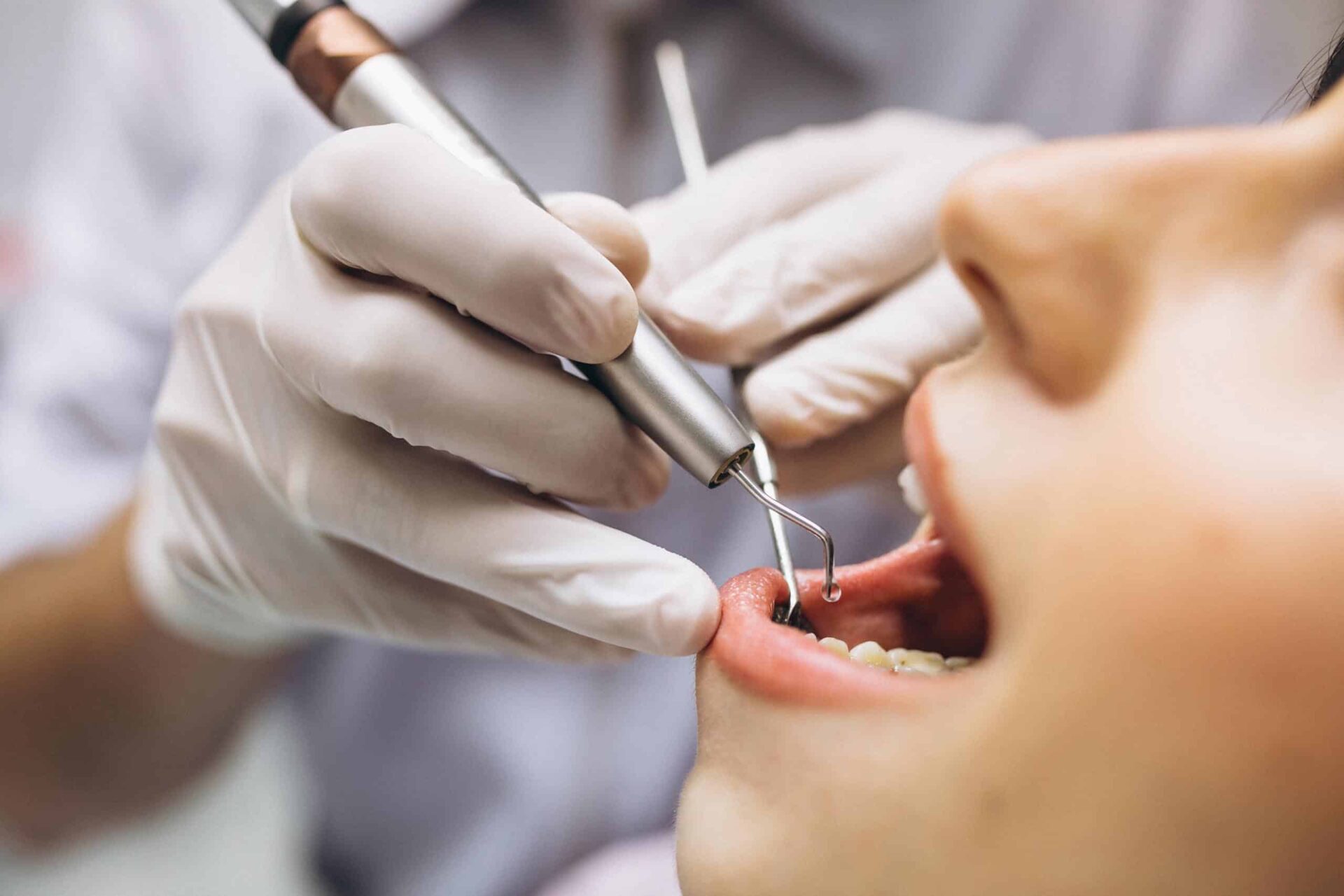 bir diş hekimi hastasının ağzını kontrol ediyor