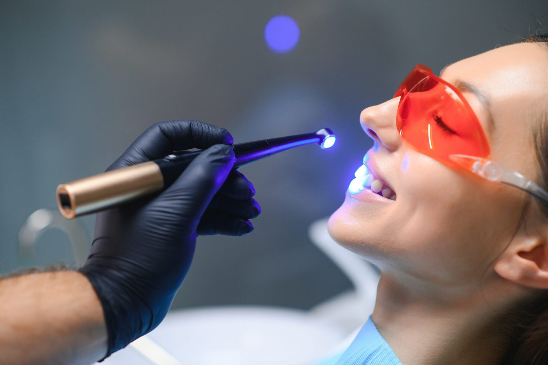 young woman getting dental filling drying procedure with curing uv light at dental clinic